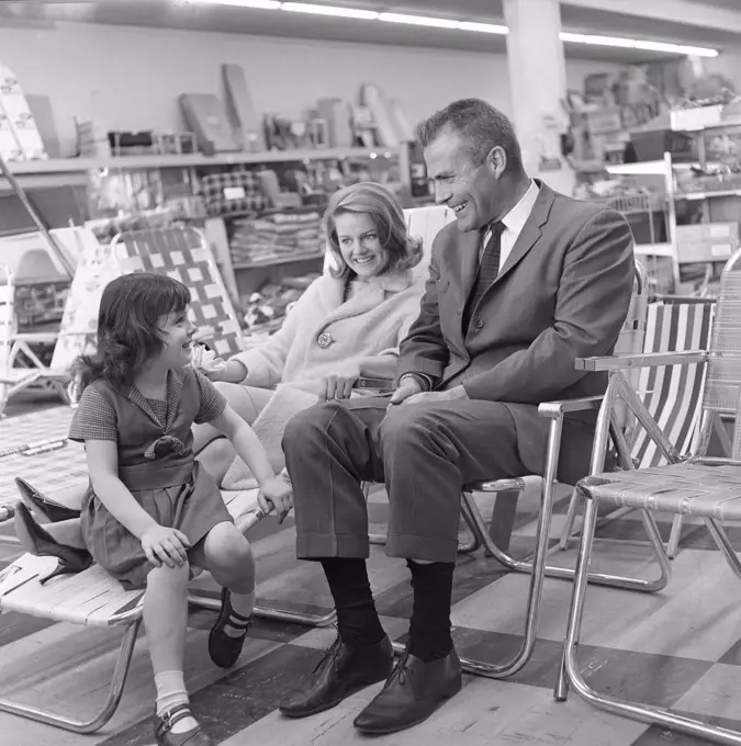 Mother and father with daughter testing deck chairs in shop