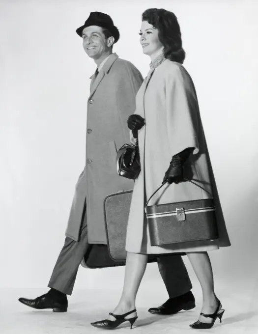 Side profile of a mid adult couple walking with luggage