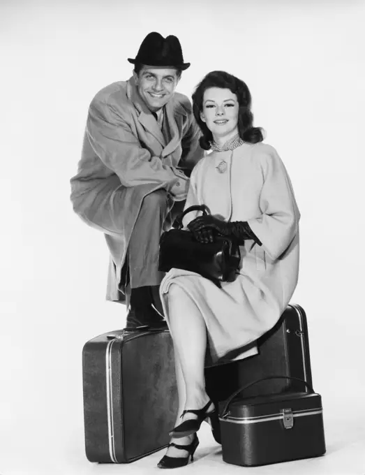 Portrait of a mid adult couple sitting with luggage