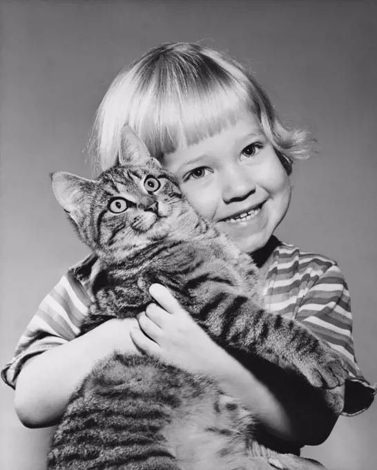 Close-up of a girl hugging a cat and smiling
