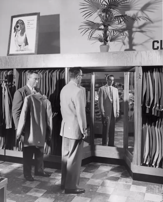 Young man trying suit in clothing store