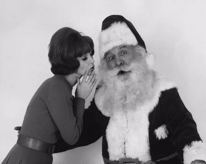 Side profile of a young woman whispering to Santa Claus