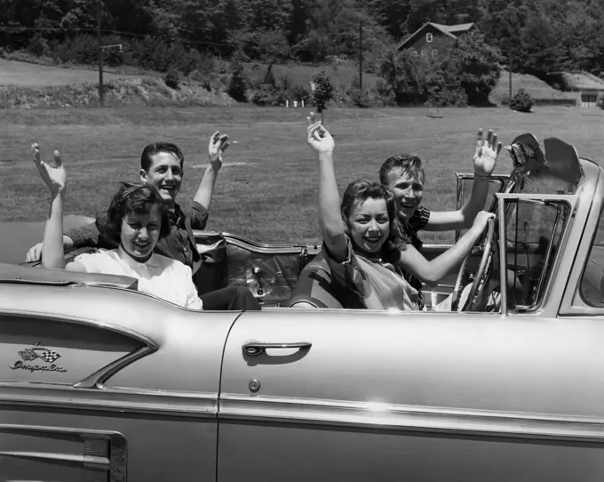 Two young couples sitting in car and waving