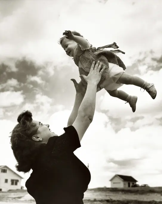 Side profile of a mother tossing her daughter in the air