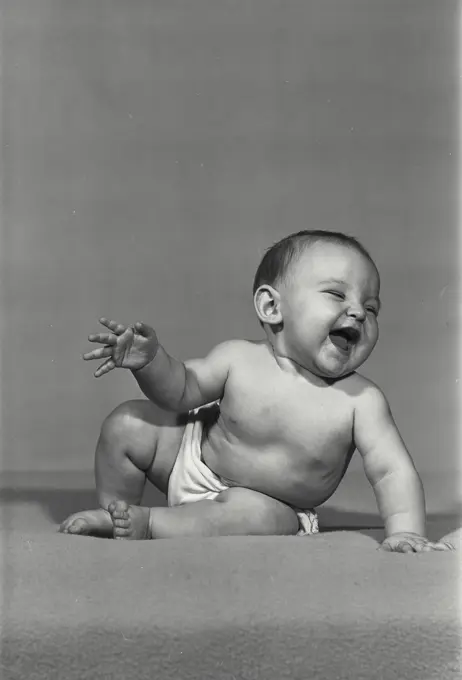 Vintage Photograph. Baby girl laughing sitting on blanket
