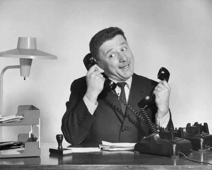 Businessman using two telephones