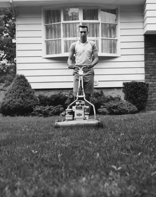 Young man cutting grass with a lawn mower