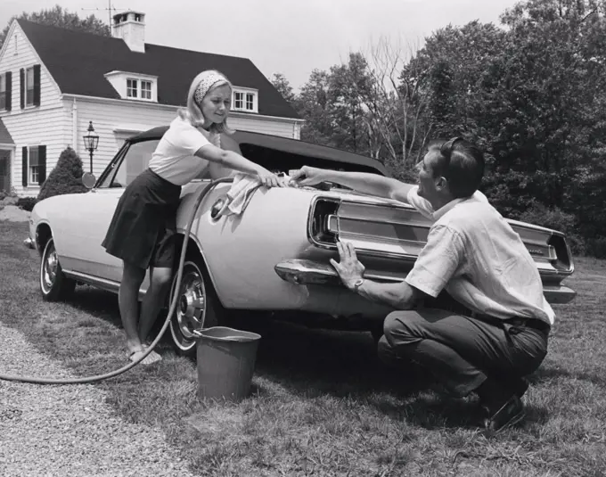 Low angle view of a mid adult couple washing a car