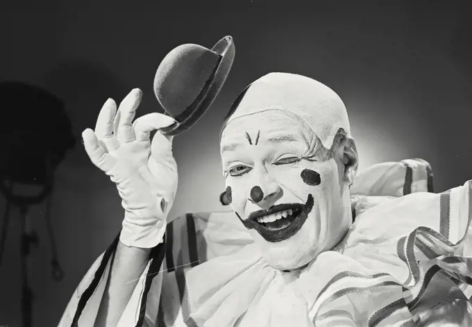 Vintage photograph. Portrait of clown putting on silly hat.