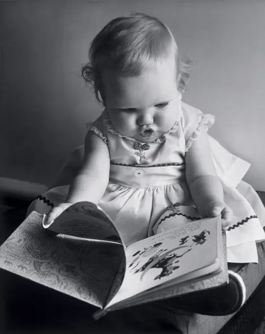 Close-up of a baby girl holding a picture book