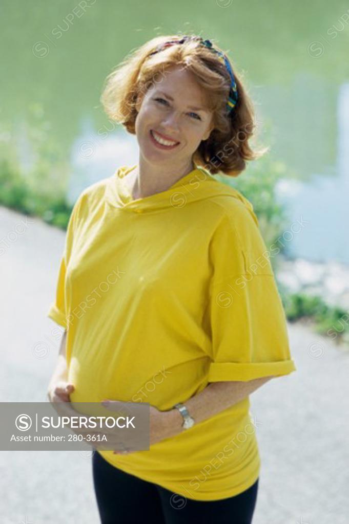 Stock Photo: 280-361A Young pregnant woman touching her abdomen and smiling