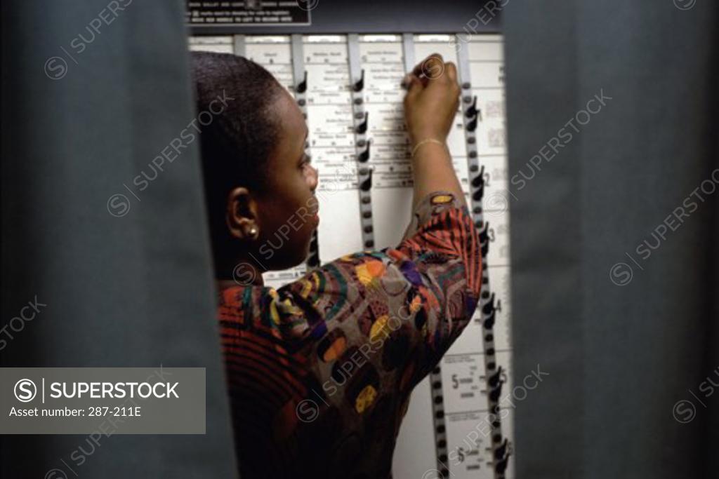 Stock Photo: 287-211E Rear view of a young woman voting in a voting booth