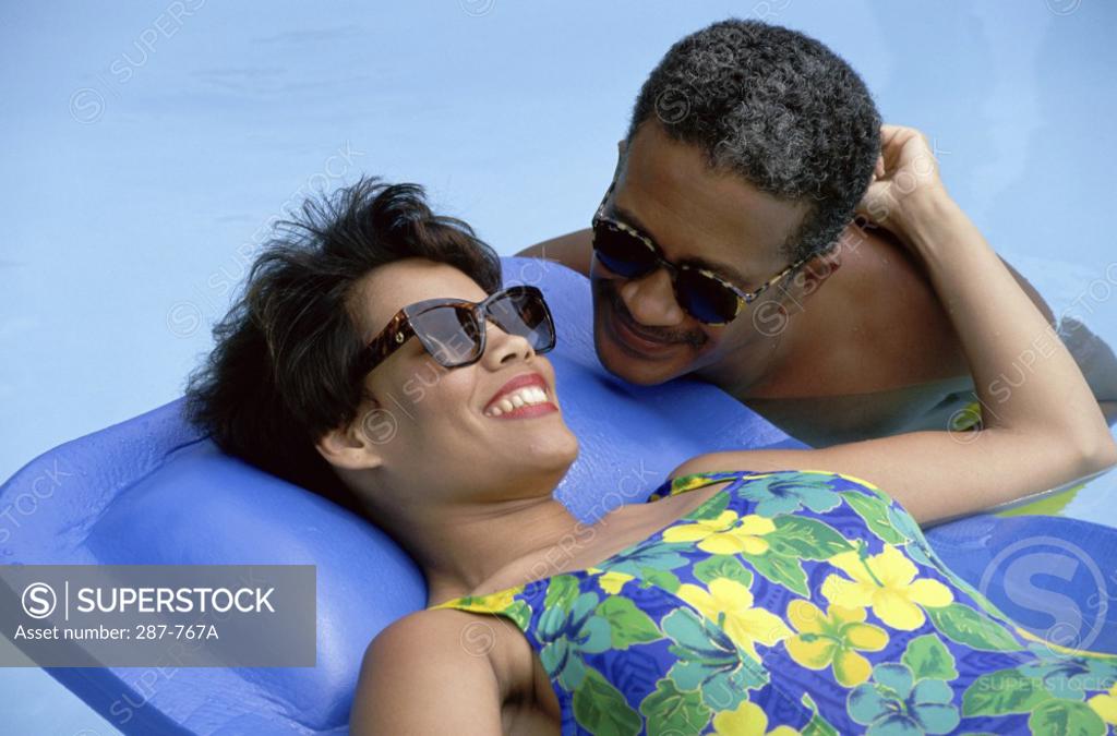 Stock Photo: 287-767A Mature woman lying on a pool raft with a mature man beside her