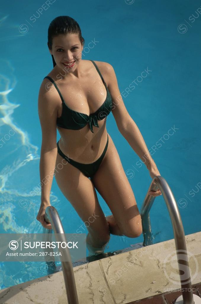 Stock Photo: 287-825A Young woman climbing out of a swimming pool and smiling
