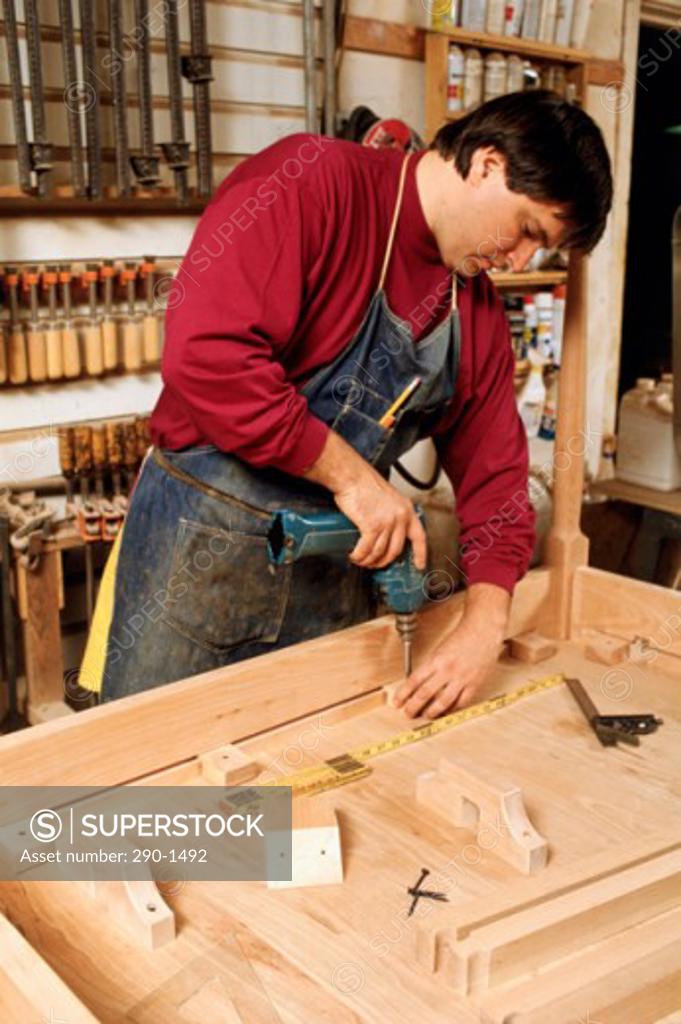 Stock Photo: 290-1492 Carpenter using an electric drill on a plank