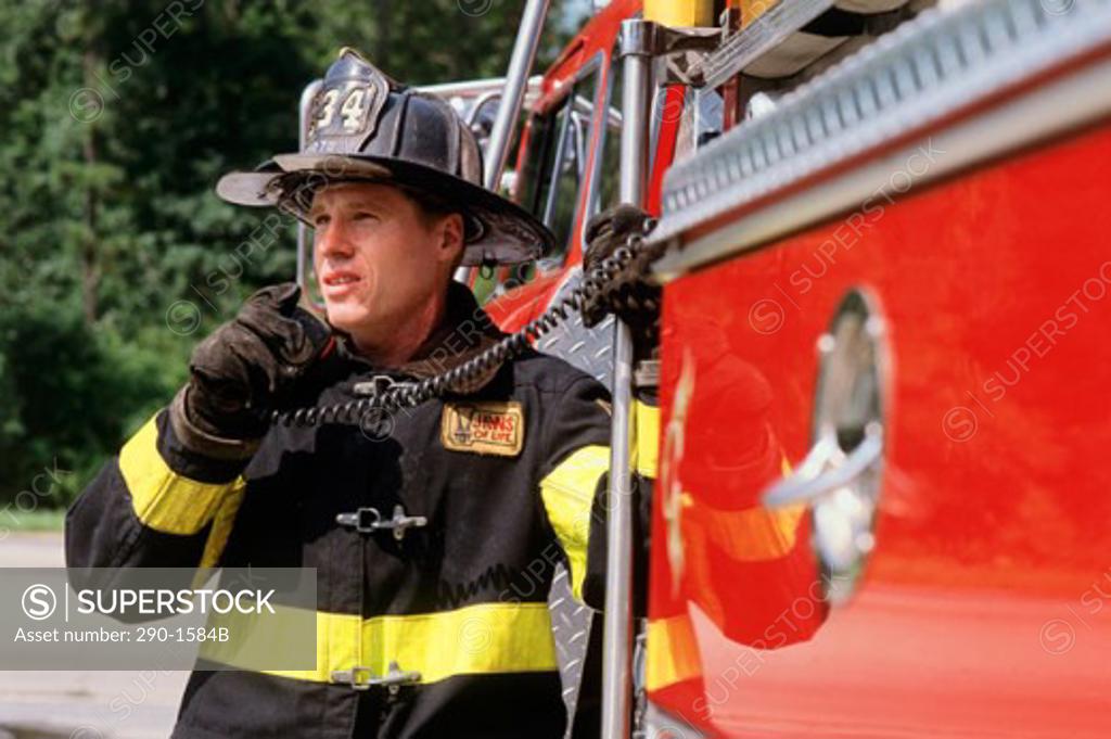 Stock Photo: 290-1584B Firefighter standing near a fire engine and talking on a walkie-talkie