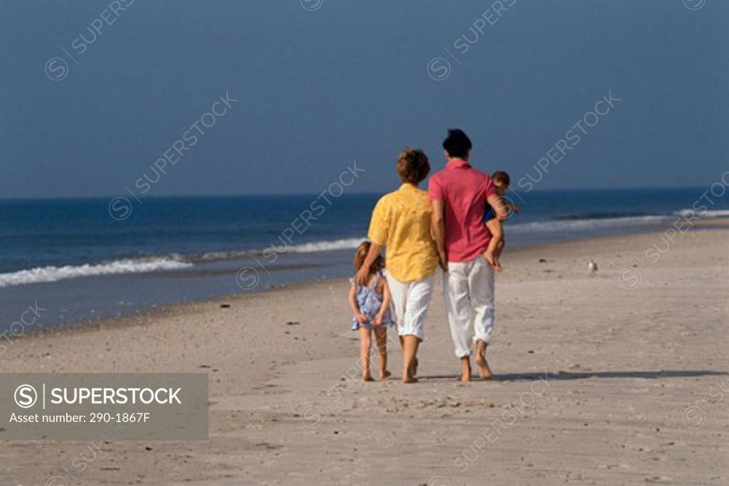 Stock Photo: 290-1867F Rear view of a man and woman with their son and daughter strolling on the beach