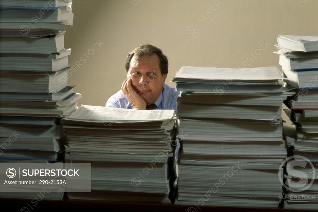 Stock Photo: 290-2153A Businessman behind stacks of files