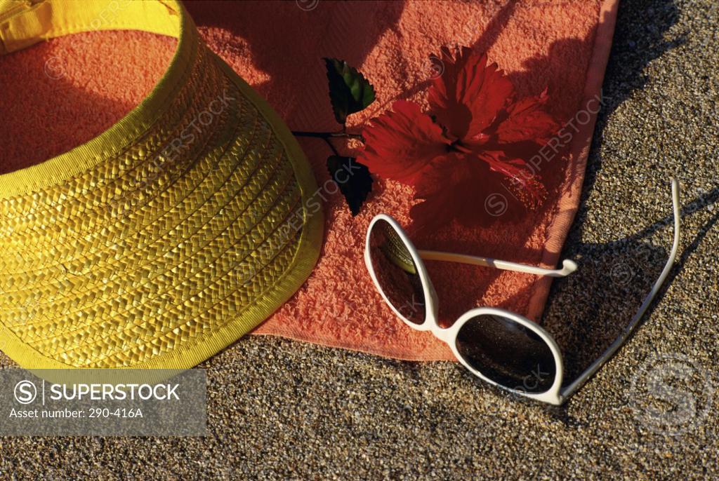 Stock Photo: 290-416A Close-up of a visor with a hibiscus and sunglasses on a beach towel