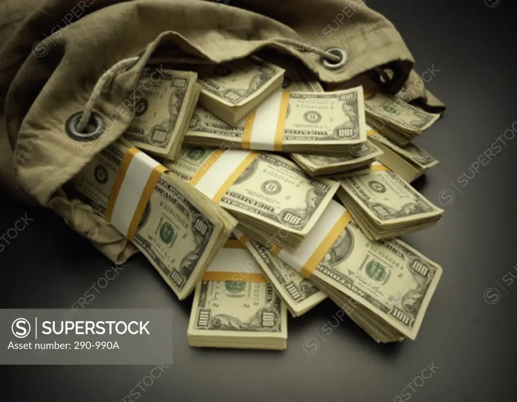 Close-up of bundles of one hundred US dollar bills spilling out from a bag