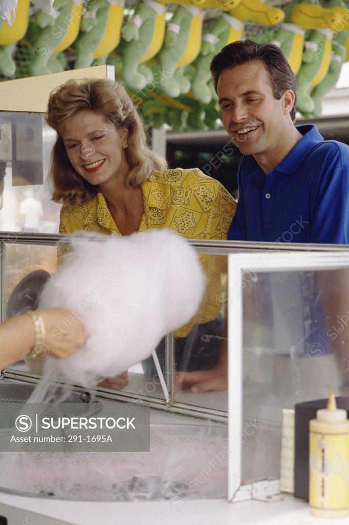 Stock Photo: 291-1695A Mid adult couple looking at cotton candy being prepared by a person