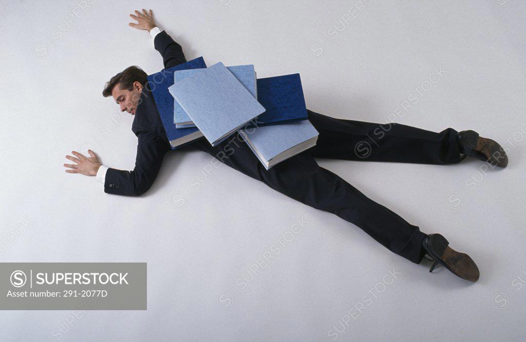 Stock Photo: 291-2077D High angle view of a businessman lying down with files on his back