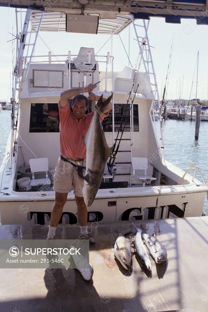 Stock Photo: 291-546C Mature man holding a fish on a dock