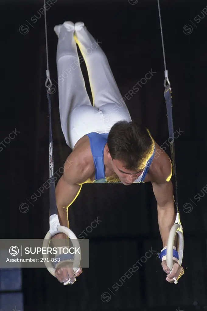 Young man doing a handstand on gymnastic rings