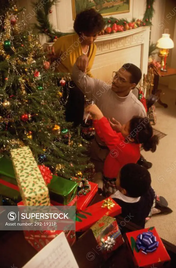 Mid adult couple with their children decorating a Christmas tree
