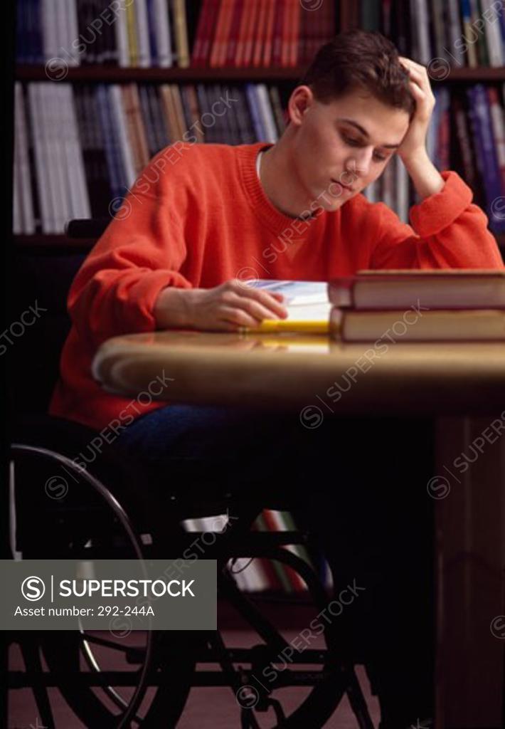 Stock Photo: 292-244A Teenage boy sitting in a wheelchair and studying