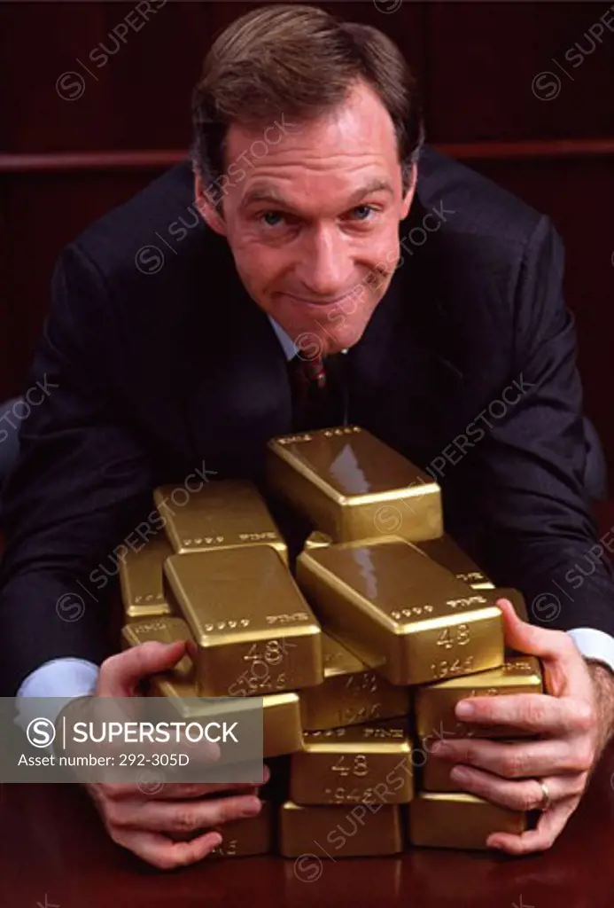 Businessman hugging a stack of gold bars