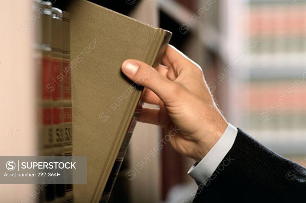 Stock Photo: 292-364H Close-up of a lawyer's hand removing a law book from shelf