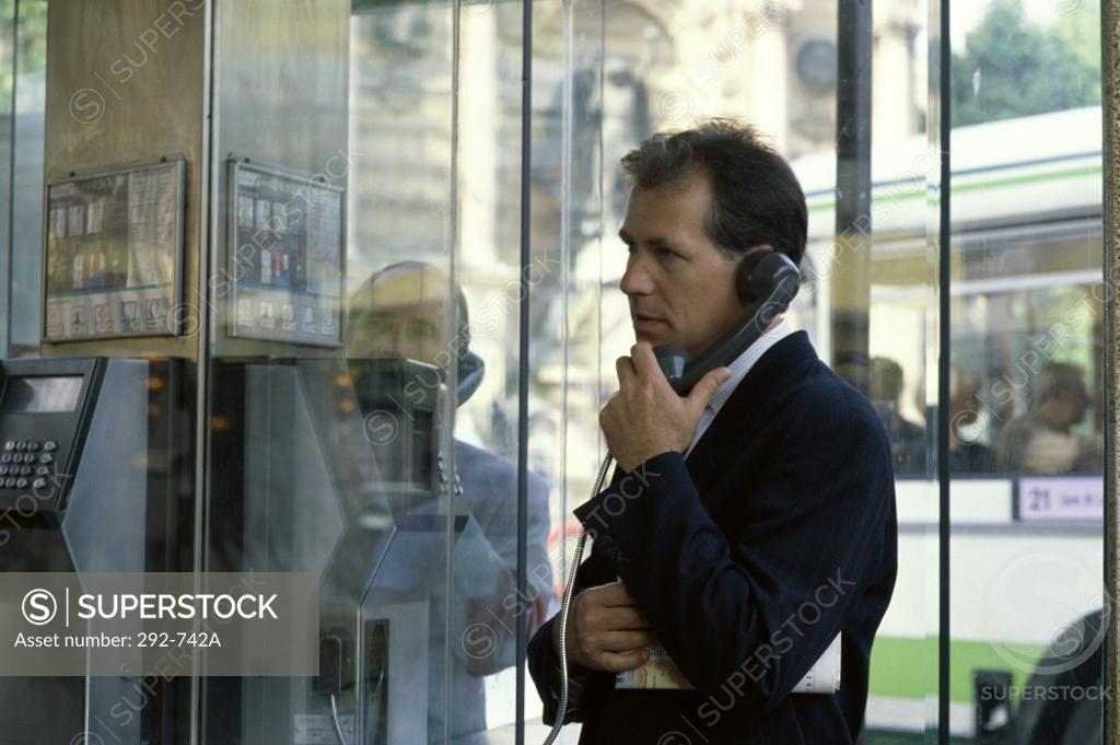 Stock Photo: 292-742A Businessman talking on a pay phone at a telephone booth