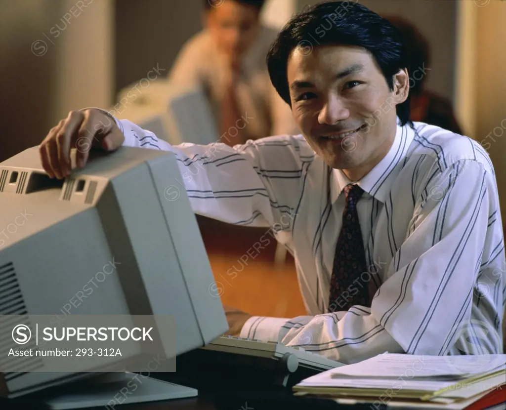 Businessman sitting in front of a computer and smiling