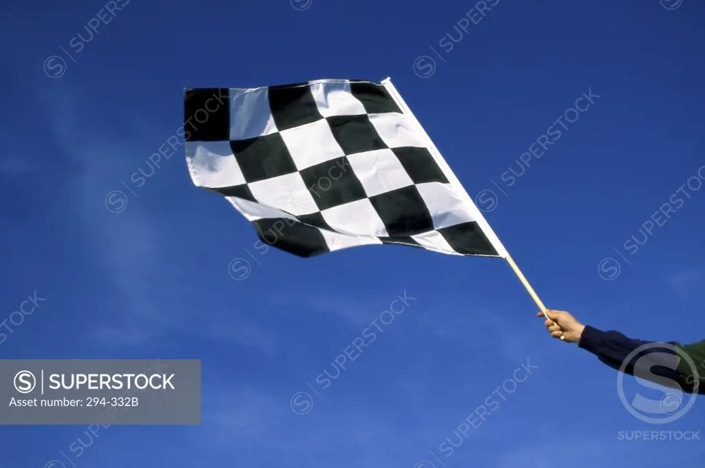 Low angle view of a man's hand waving a checkered flag
