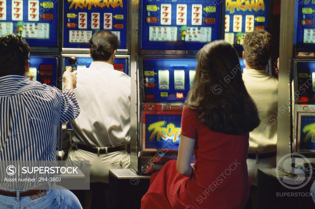 Stock Photo: 294-380J Rear view of a woman with three men playing slot machine in a casino