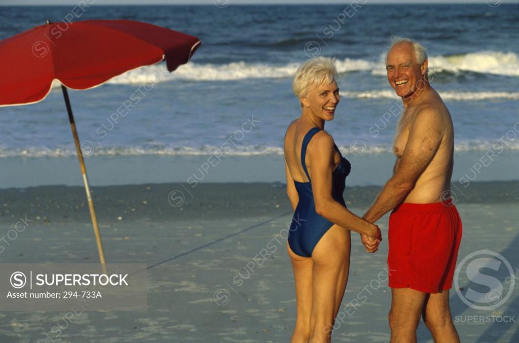 Stock Photo: 294-733A Senior couple standing on the beach and holding hands