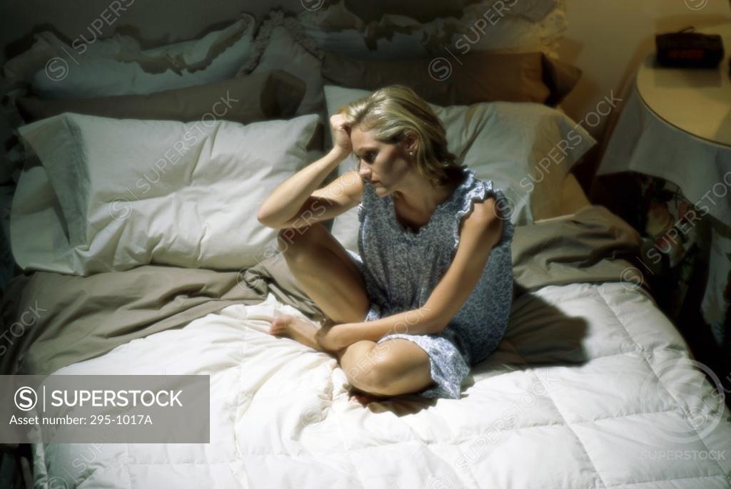Stock Photo: 295-1017A High angle view of a young woman sitting on the bed and looking upset