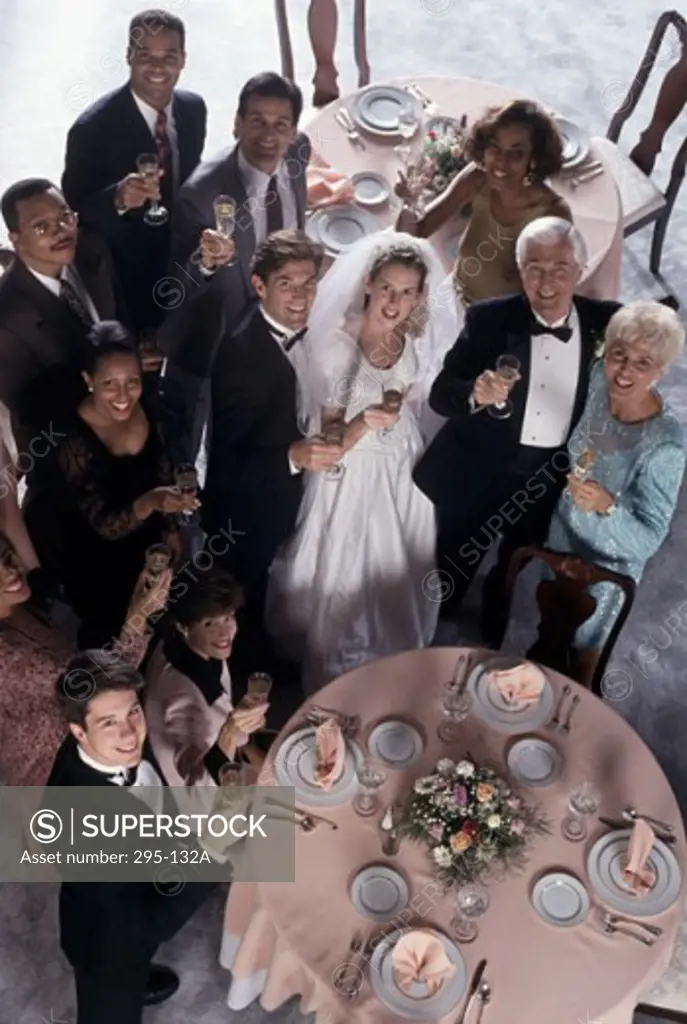 Portrait of a newlywed couple standing with their parents and wedding guests holding champagne flutes