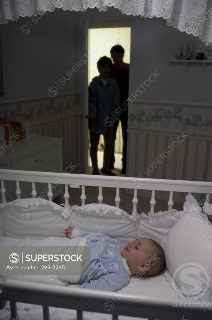 Stock Photo: 295-226D Silhouette of a young couple peeking at their son sleeping in a crib