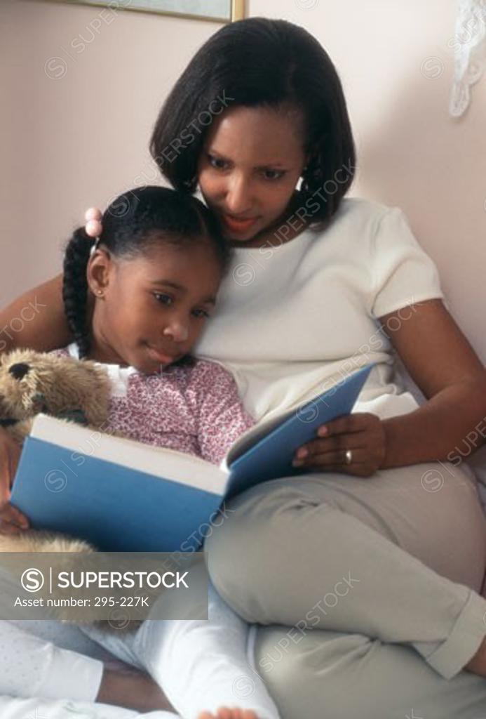 Stock Photo: 295-227K Woman and her daughter reading a book