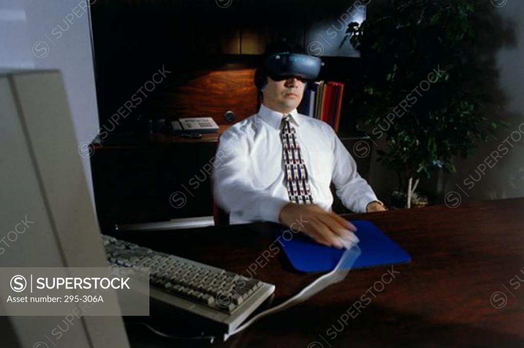 Stock Photo: 295-306A Businessman wearing a virtual reality simulator and using a computer