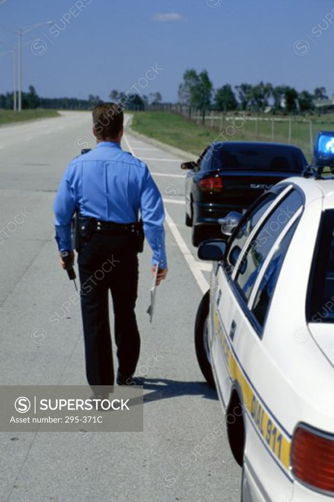 Stock Photo: 295-371C Rear view of a police officer walking on the road