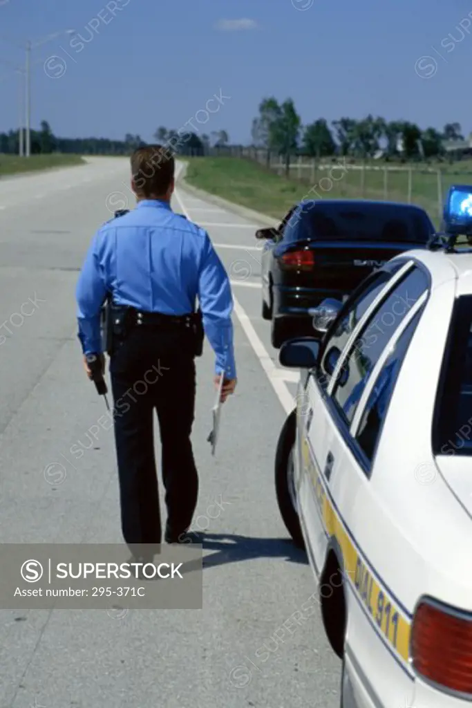 Rear view of a police officer walking on the road
