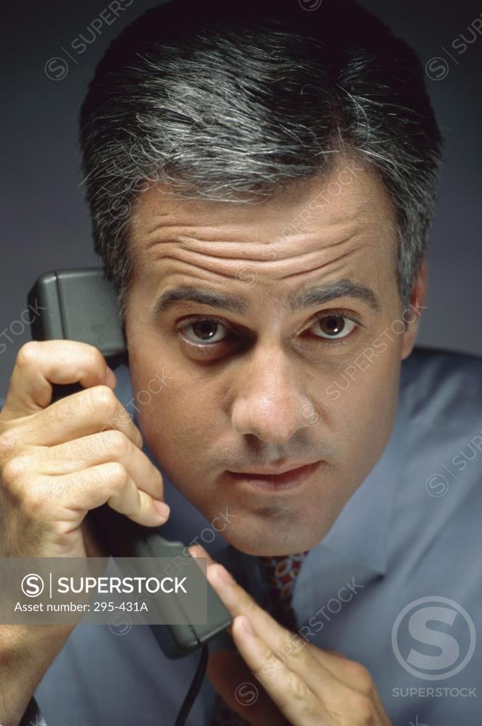 Stock Photo: 295-431A Portrait of a businessman holding a telephone receiver and covering its mouthpiece with his hand