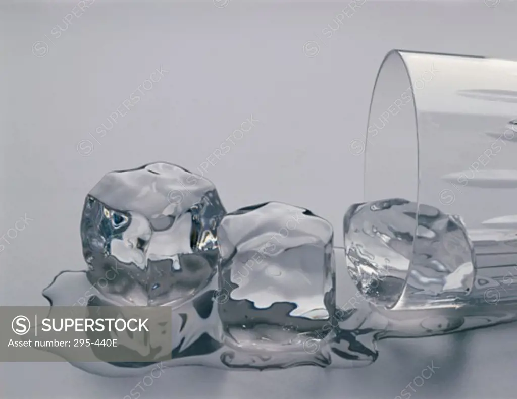 Close-up of three melting ice cubes spilling out from a fallen glass