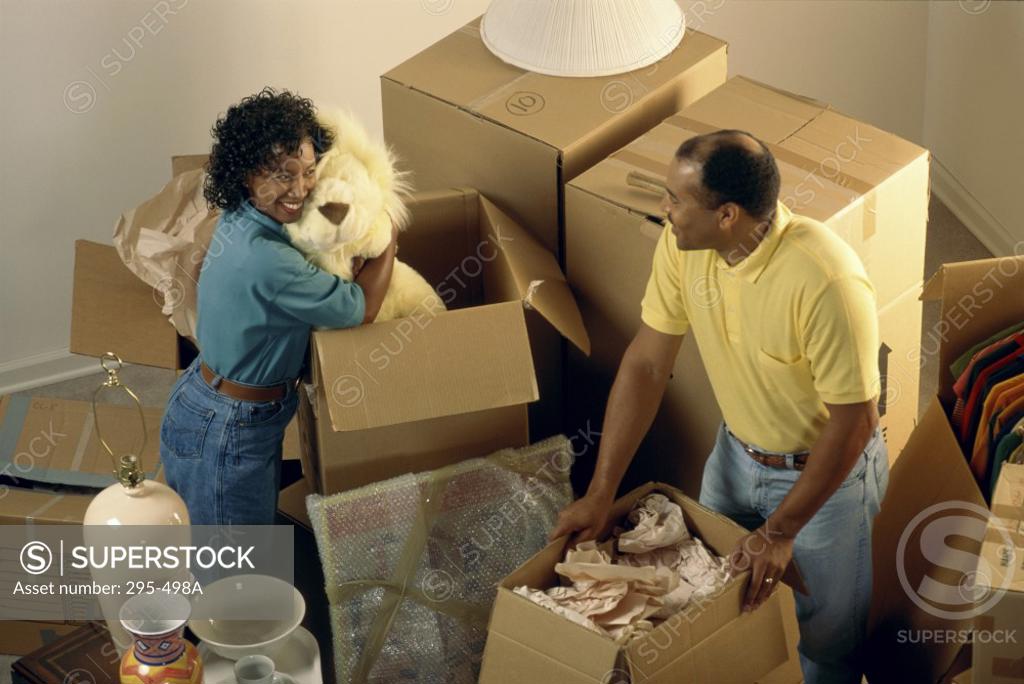 Stock Photo: 295-498A Mid adult couple unpacking cardboard boxes and smiling in their new house