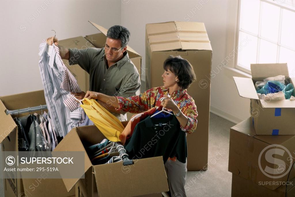 Stock Photo: 295-519A Mid adult couple unpacking cardboard boxes in their new house