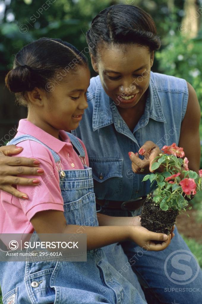 Stock Photo: 295-601A Girl holding a plant with her mother standing beside her