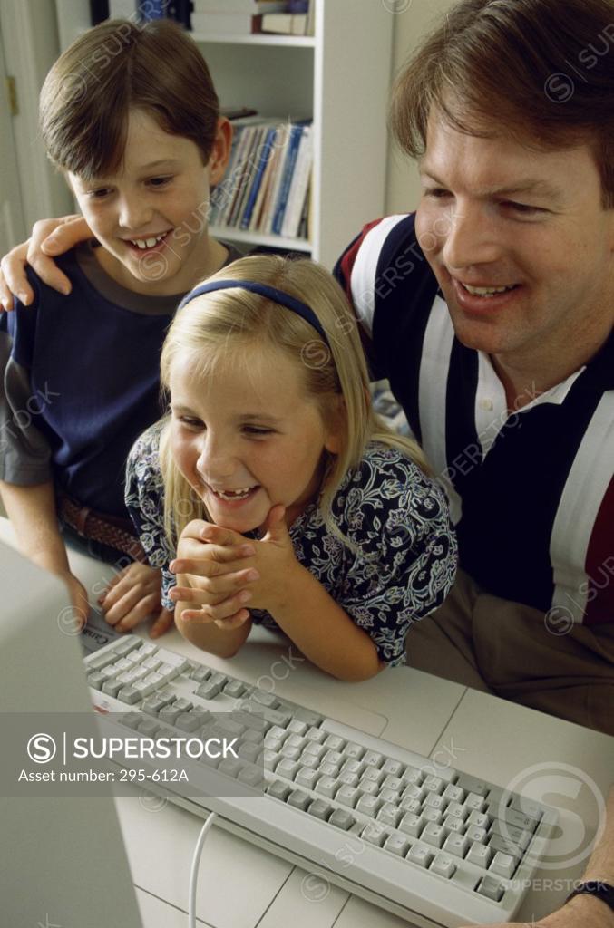 Stock Photo: 295-612A Mid adult man with his son and daughter sitting in front of a computer